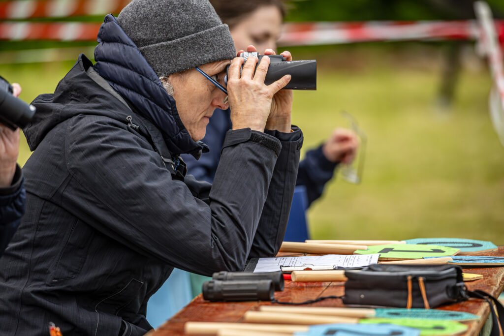 Kampfrichterin beobachtet die Scheiben mit dem Fernglas