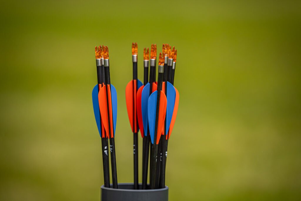 Pfeile mit blauen und orangefarbenen Federn in einem Rohr